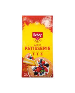 Dr. Schär bezglutensko brašno za kolače i kekse Mix C - Mix Pâtisserie 1 kg - ovo svilenkasto mekano bijelo brašno je stvoreno kako bi donijelo dozu slatkoga u vaš dan. Crveno žuto pakiranje brašna na bijeloj pozadini.